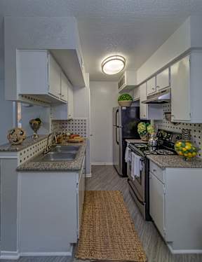 A kitchen with white cabinets and a black refrigerator.
